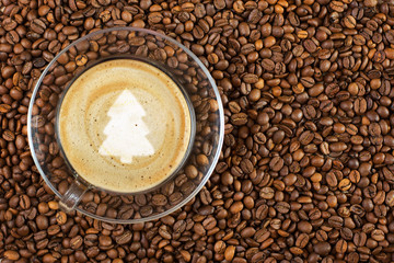 Cup of espresso with christmas treesign on coffee foam on coffee beans background. With copy space