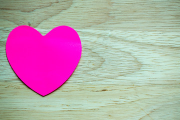 Wall Mural - Pink stick note isolated on wood background.paper heart shape on wood texture with copy space. Image for Valentines day.symbol of love. use to greeting card and background.horizontal.