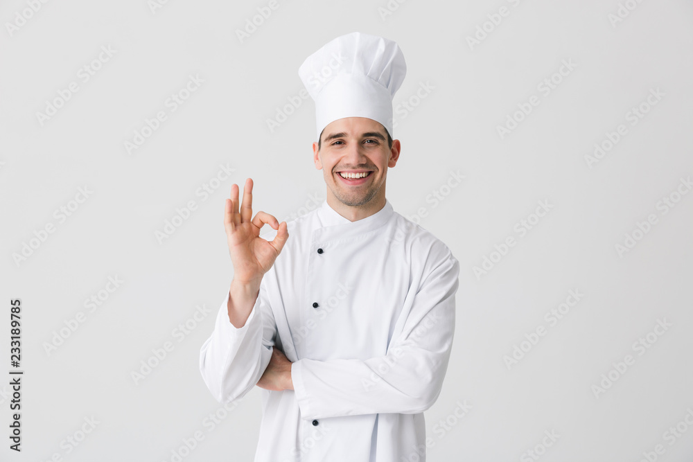 Handsome young man chef indoors isolated over white wall background. - obrazy, fototapety, plakaty 