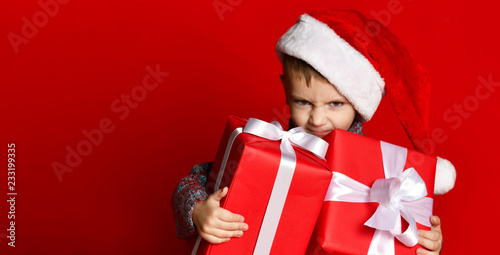 Fotomural Funny smiling child in Santa red hat holding Christmas gift in hand