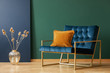 © Photographee.eu - Brown cushion on blue armchair in green living room interior with flowers in gold vase. Real photo