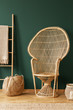 © Photographee.eu - Peacock rattan chair next to bag and ladder in green flat interior with blanket and rug. Real photo