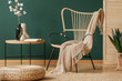© Photographee.eu - Pouf in front of table with flowers next to armchair with blanket in green loft interior. Real photo