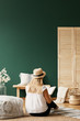 © Photographee.eu - Woman reading book on carpet next to pouf in green living room interior with flowers. Real photo