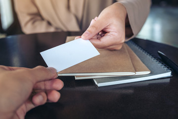 Businesswoman exchange business card with notebooks on table in office