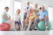 Happy senior people sitting on balls after physical classes in the studio