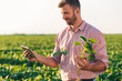 © Zoran Zeremski - Young farmer standing in filed holding tablet in his hands and examining soybean corp.