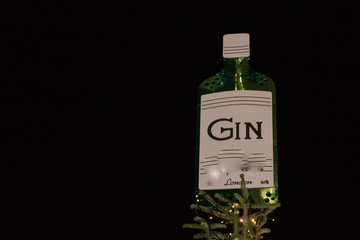 Top of Christmas tree in London’s evening street is decorated with a bottle of gin. Gin is a traditional alcoholic drink in the UK. Concept: Merry Christmas and Happy New Year holidays.