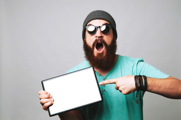 Wall Mural - Amazed man with beard pointing at tablet