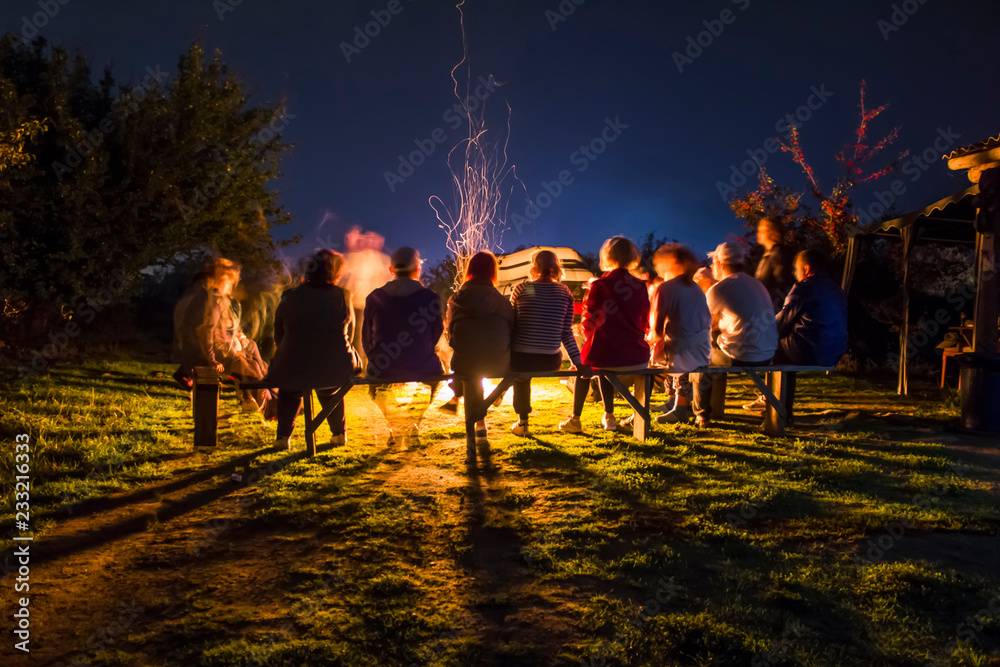 People rest near a bonfire on the nigt. long exposure - obrazy, fototapety, plakaty 