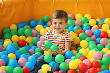 Cute little child playing in ball pit at indoor amusement park