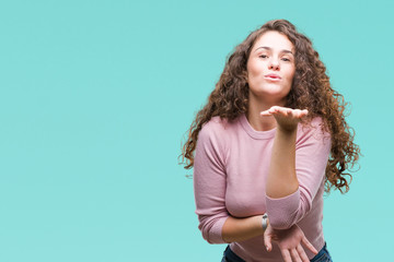 Sticker - Beautiful brunette curly hair young girl wearing pink sweater over isolated background looking at the camera blowing a kiss with hand on air being lovely and sexy. Love expression.