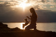 © ruslanshug - silhouette of young woman training chihuahua small dog on sea sunset background