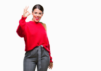 Sticker - Young beautiful business woman wearing winter sweater over isolated background smiling positive doing ok sign with hand and fingers. Successful expression.