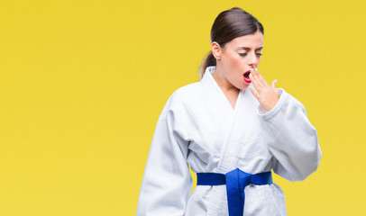 Poster - Young beautiful woman wearing karate kimono uniform over isolated background bored yawning tired covering mouth with hand. Restless and sleepiness.