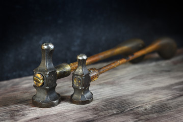 Wall Mural - two old vintage hammers from a goldsmith on a wooden workbench against a dark background with copy space, close up