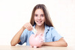 © 5second - Young girl with pink piggybank and dollar banknote sitting at table