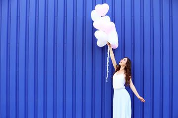 Wall Mural - Cute girl with heart balloons on blue background