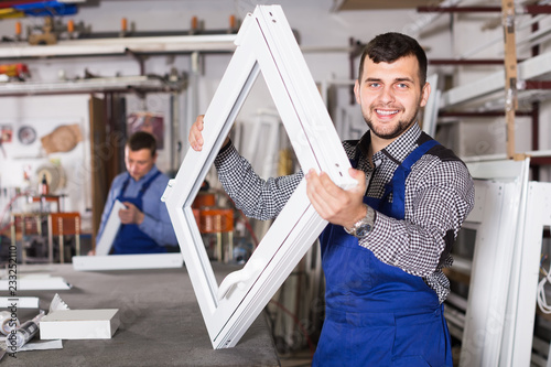 Fotografía happy male professional labours with finished PVC profiles and windows