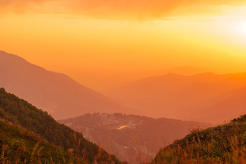 Wall Mural - view of a beautiful mountain valley with a small town in the sunrise rays