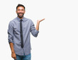 © Krakenimages.com - Adult hispanic business man over isolated background smiling cheerful presenting and pointing with palm of hand looking at the camera.