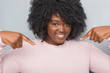 © Krakenimages.com - Young african american plus size woman over grey grunge wall wearing winter sweater looking confident with smile on face, pointing oneself with fingers proud and happy.