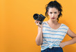 © Tierney - Young woman with a professional digital SLR camera on a yellow background