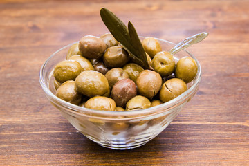 Bowl with olives and olive branch on a wooden table