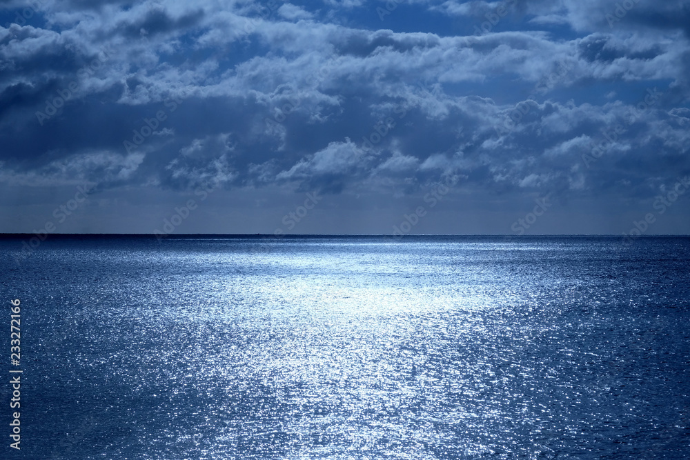 shimmering sea and sky with clouds lit by moonlight Stock