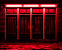 Red Light District In Amsterdam. Red Boxes With Curtains And Wet Cobbles On The Street