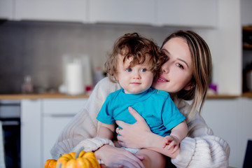 Wall Mural - Happy white mother and son with pumpkin. Domestic image at kitchen