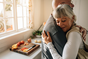 Wall Mural - Senior man and woman embracing standing at home