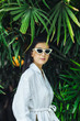 © LUMINA IMAGES - Young woman wearing sunglasses standing by  leafage