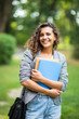 © F8  \ Suport Ukraine - Pretty cheerful latin american student smiling at camera carrying notebook on campus at college