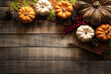 Wall Mural - top view of autumn maple leaves with pumpkin and red berries on old wooden background. thanksgiving 