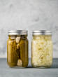 Pickled cucumbers and Sauerkraut on gray background with copy space for text. Perfect homemade marinated cucumbers and pickling cabbage in mason jar at home on table. Vertical