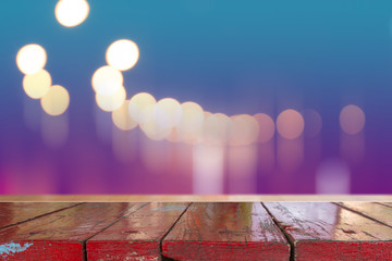 Canvas Print - wooden desk with blurred light on road in city with bokeh abstract background