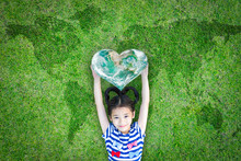 World Kindness Day Concept With Happy Kid Raising Heart Planet On Ecological Friendly Natural Green Lawn. Element Of The Image Furnished By NASA