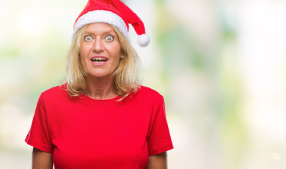 Canvas Print - Middle age blonde woman wearing christmas hat over isolated background afraid and shocked with surprise expression, fear and excited face.