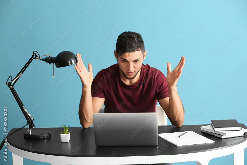 Emotional young man after making mistake during work with laptop