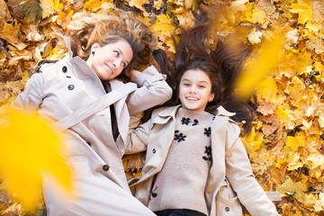 Happy mother and daughter are walking in the autumn park