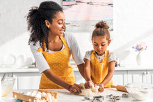 Attractive African American Mother And Adorable Daughter Kneading Dough In Kitchen