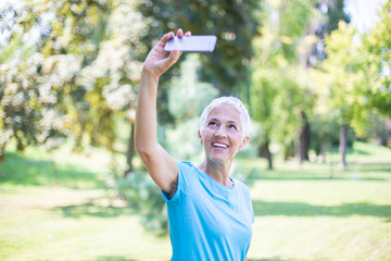 Wall Mural - Sporty senior woman taking selfie with mobile phone