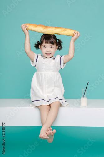 Fotografie, Tablou Little pretty Asian girl laughing portrait with milk and bread, healthy and happy lifestyle