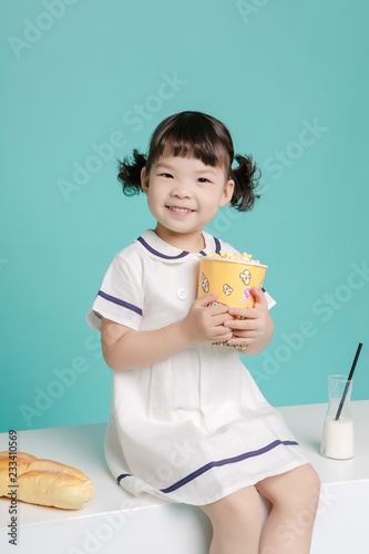 Fotografie, Tablou Little pretty Asian girl laughing portrait with milk and bread, healthy and happy lifestyle