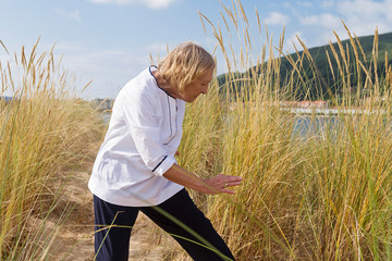 A senior woman practicing Tai Chi in a beach