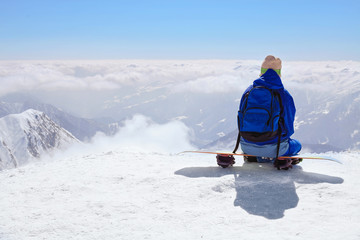 snow border sit on the top of the hill on his board  in nice sunny day. Caucasus Mountains in winter, Georgia, region Gudauri, Mount Kudebi.