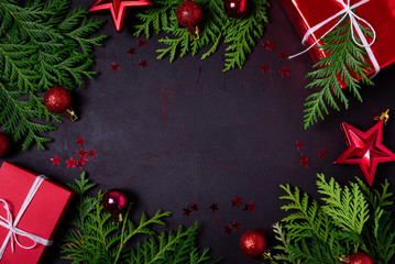 Sticker - Christmas frame of red gift boxes, fir branches, confetti and toys on black background. Flat lay. Top view. Copy space