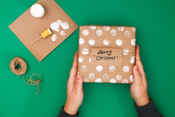 The original design of a Christmas gift of craft paper, white paint, a stamp of potatoes. Step by step on the photo. Handmade, DIY. A gift wrapped in brown paper with white polka dots.