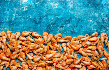 Many small boiled shrimps on a blue background